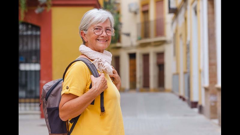 An older traveller smiles at the camera during her holiday