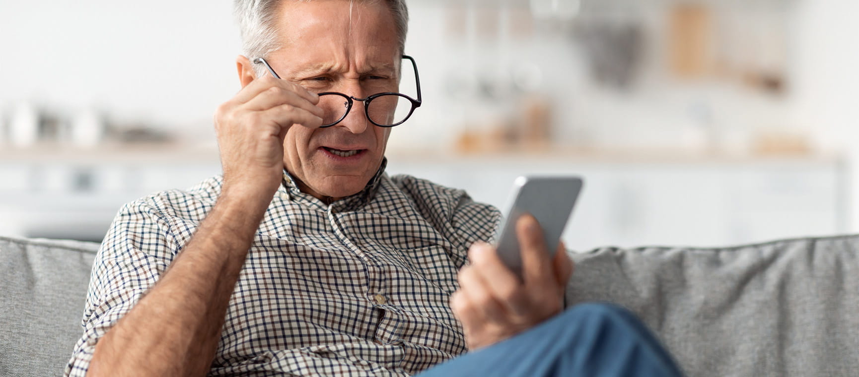 An older man squinting through his glasses at his phone