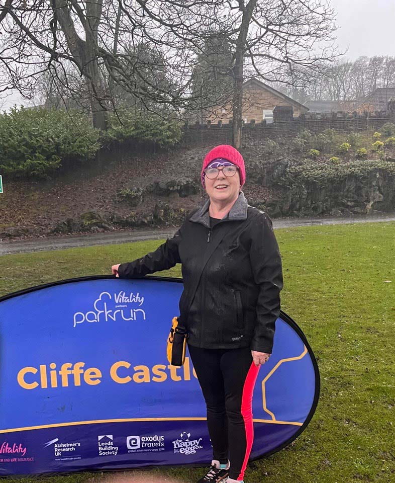 A woman standing in front of a fun run sign