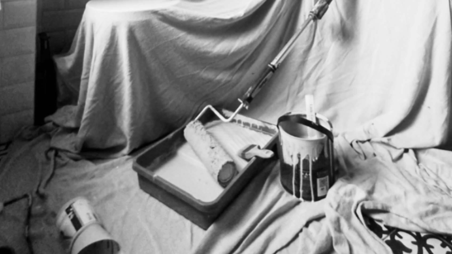 A paint roller with tray on top of protective dust sheets