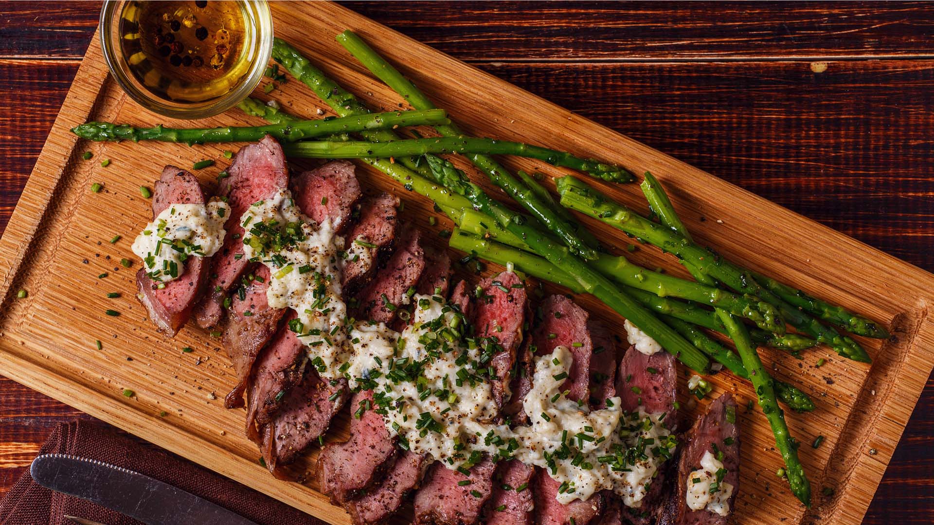 Rare steak laid out on a board with asparagus