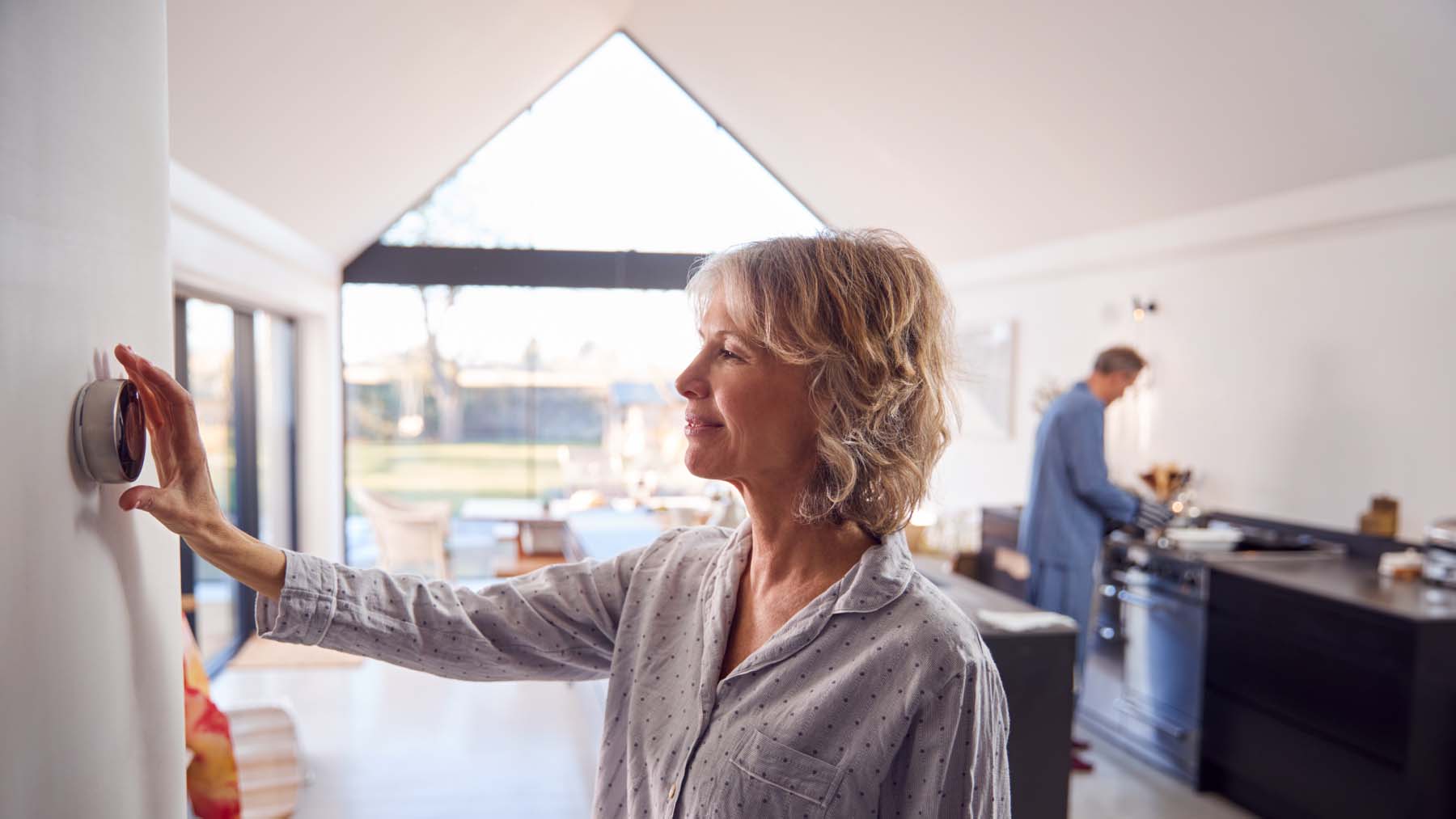 woman turning down the thermostat at home