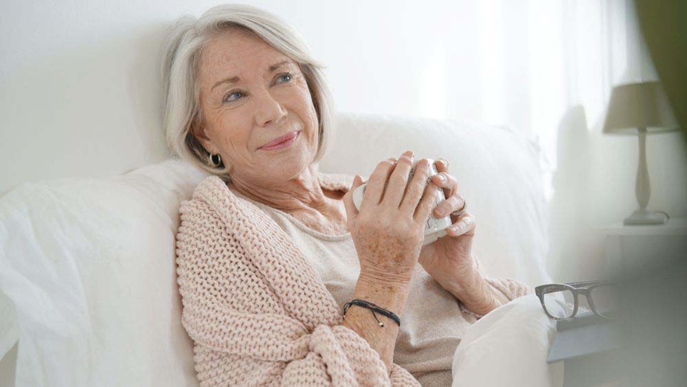 A woman wrapped in a blanket holding a mug