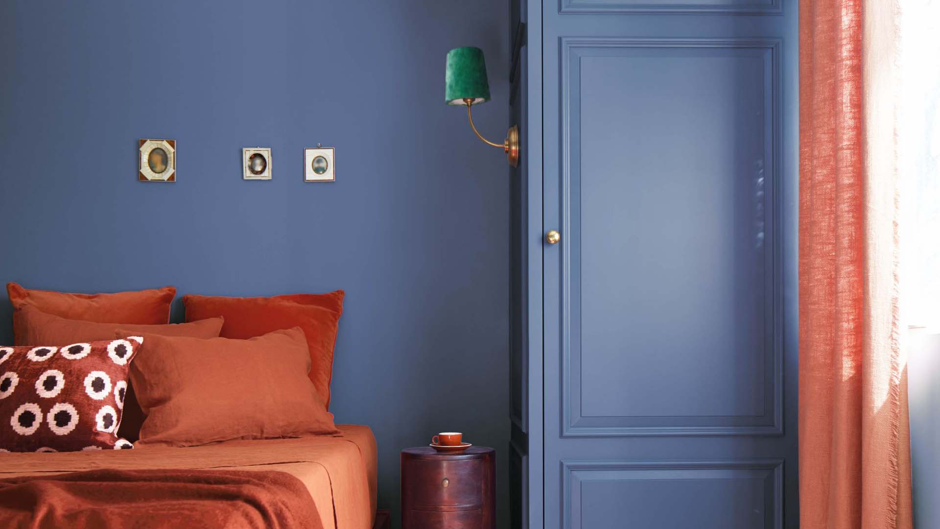 A bedroom with an orange bed and blue walls and furniture