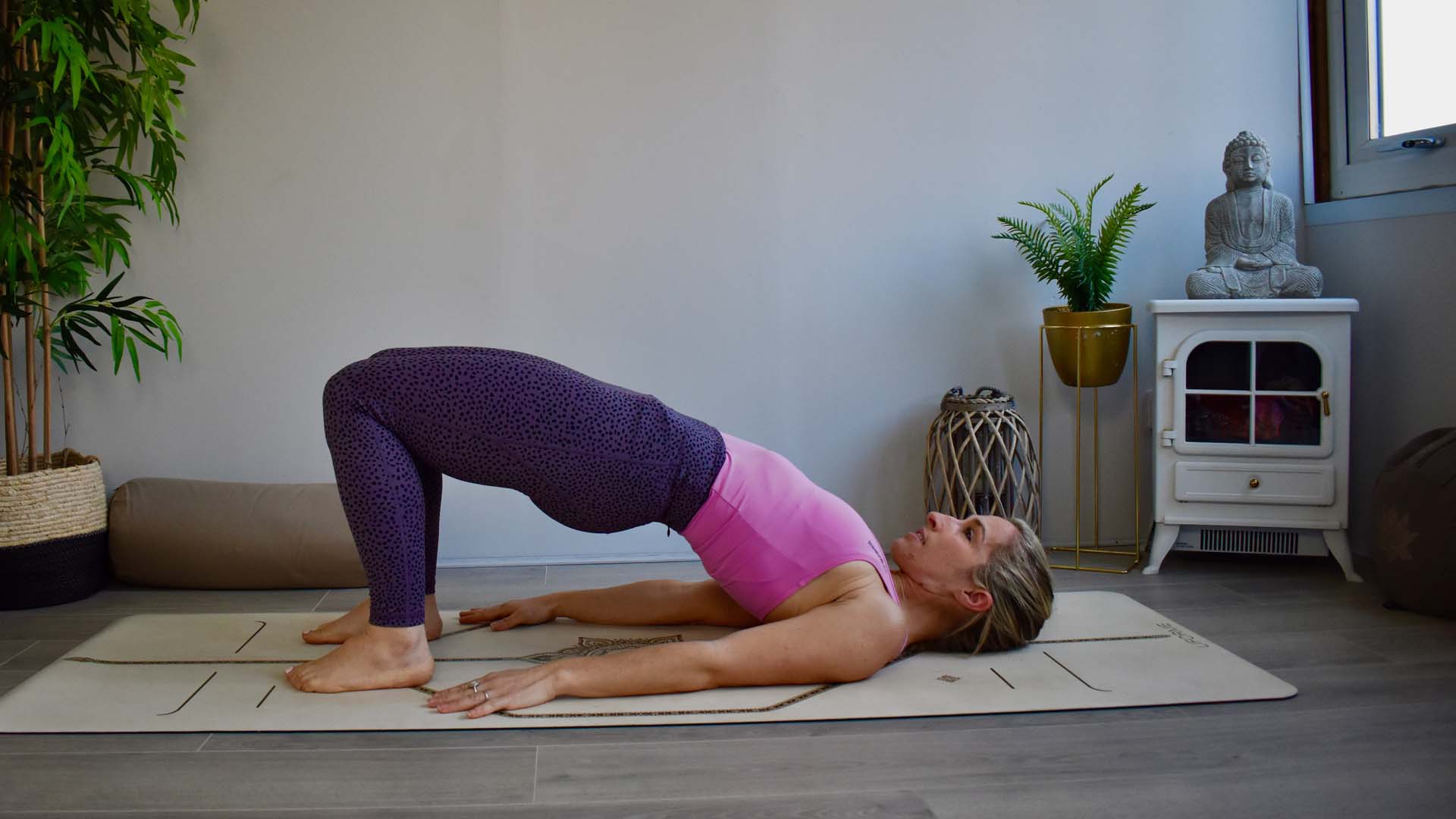 A woman on a yoga mat in Bridge posture illustrating one of the best beginner yoga poses