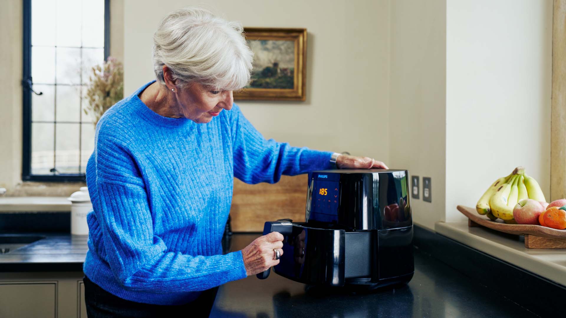 A woman removing the air fryer tray