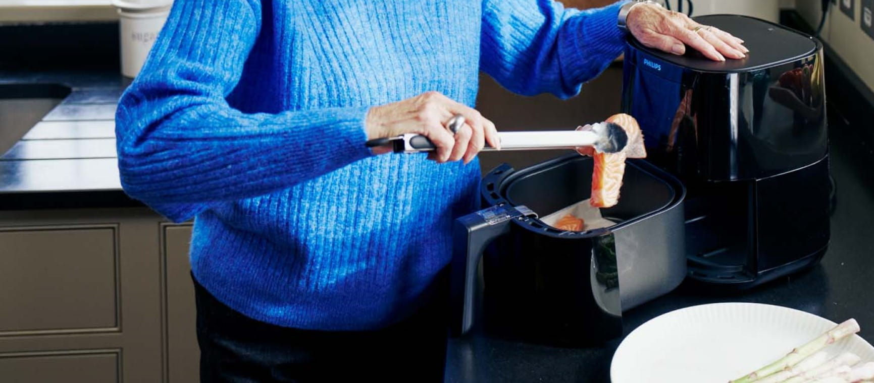 A woman cooking salmon in an air fryer