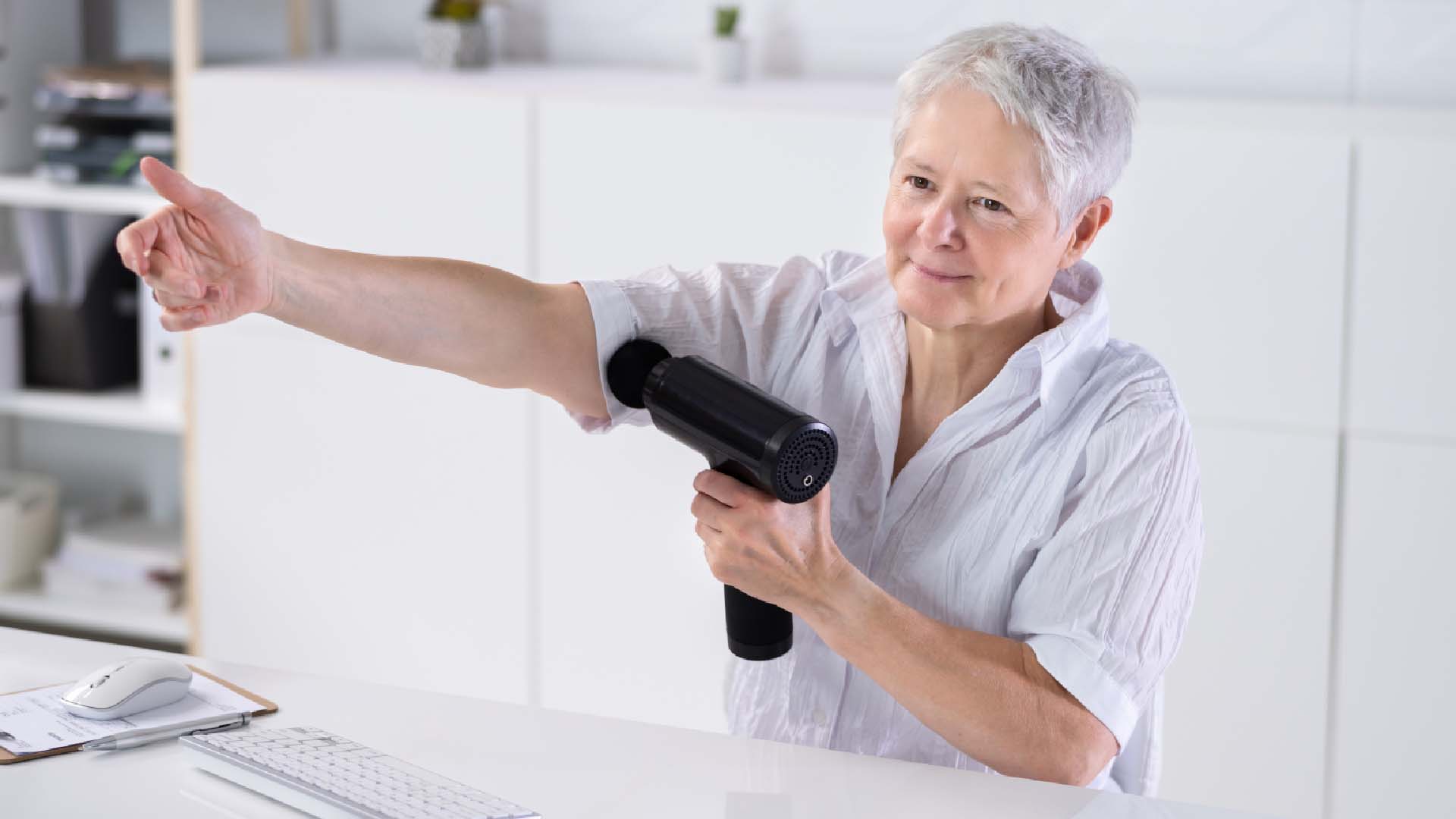 woman using a massage gun on her arms