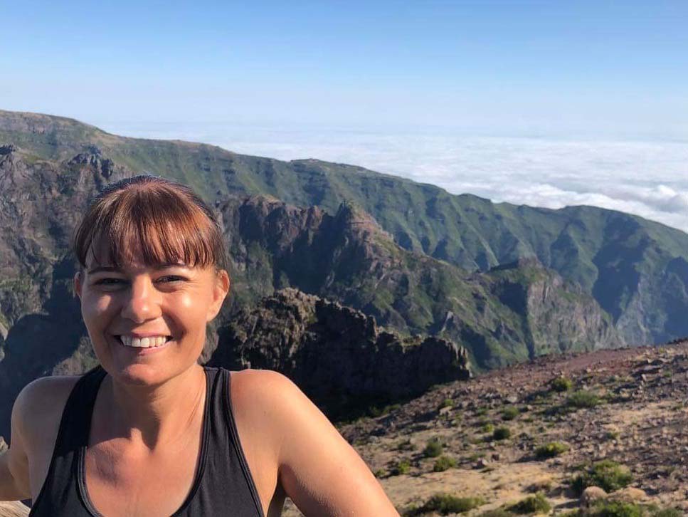 mountain leader Kerry Crosford poses with mountains as a backdrop