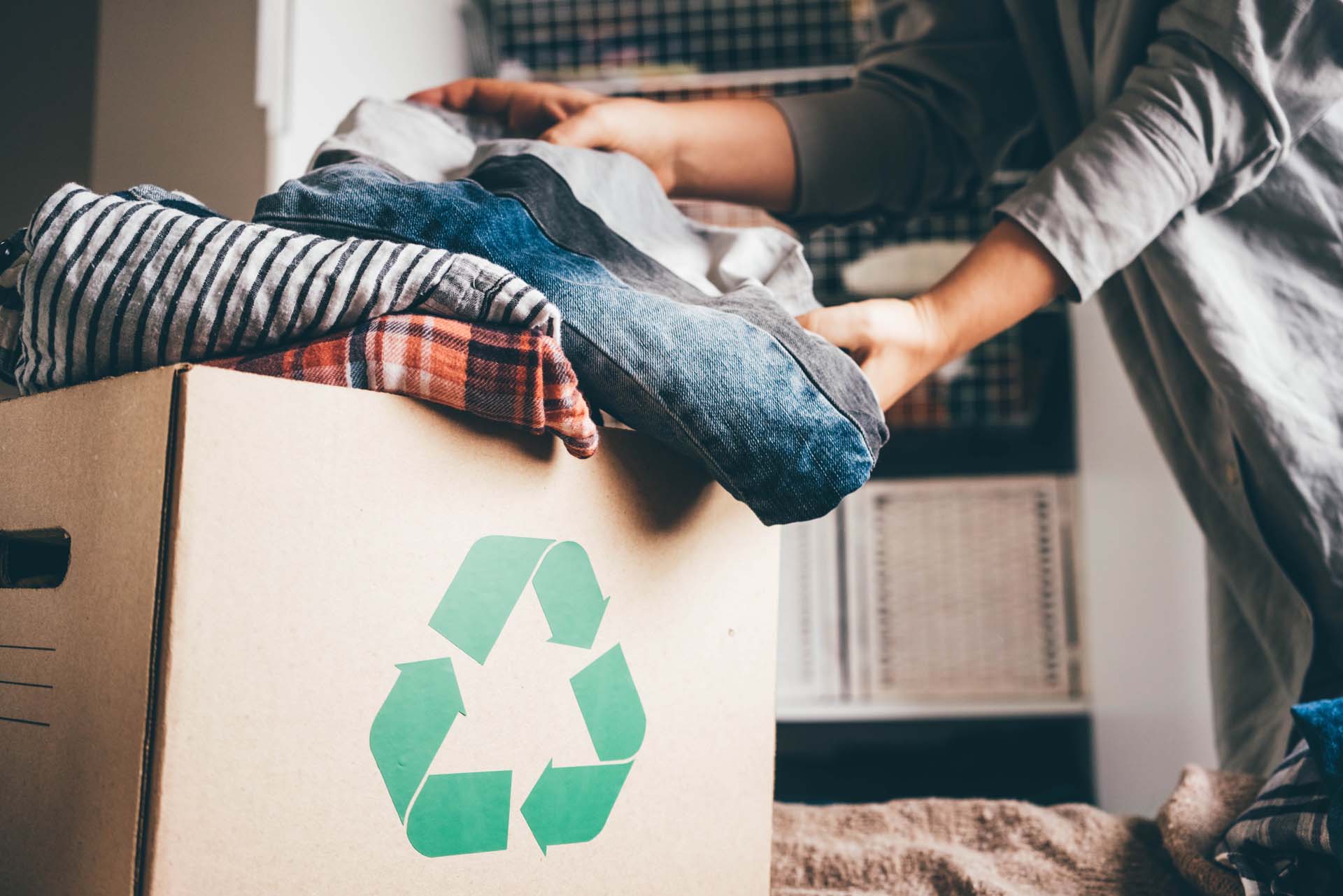 A person putting old clothes into a box to be recycled