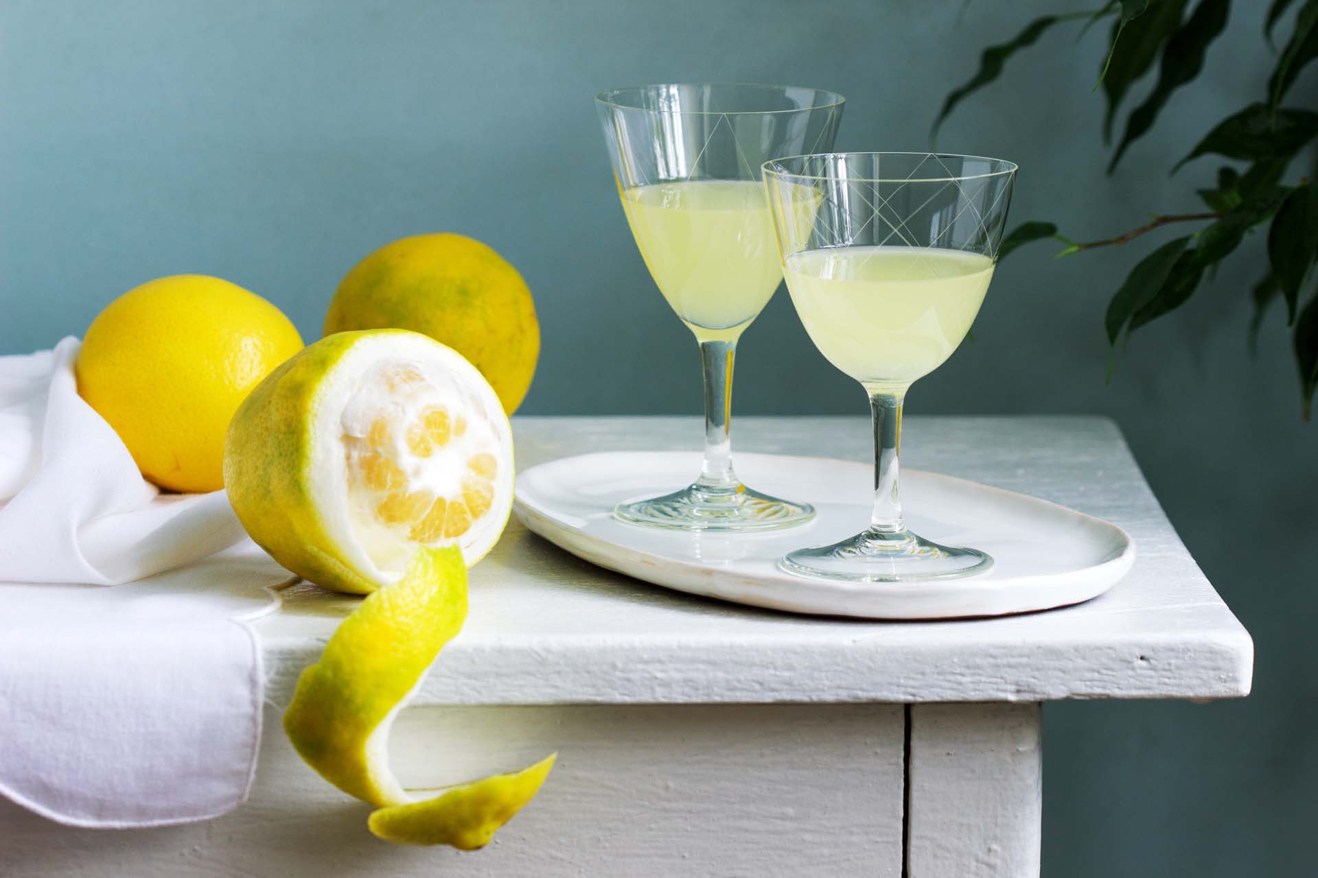 A half peeled lemon and two glasses of lemon juice