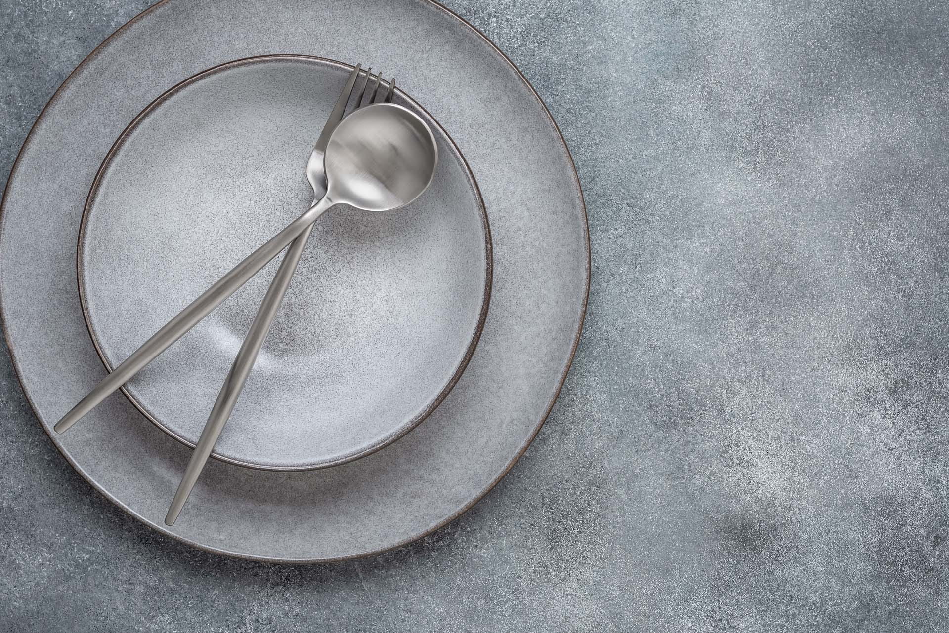 Gray plates and silvery cutlery on a gray background