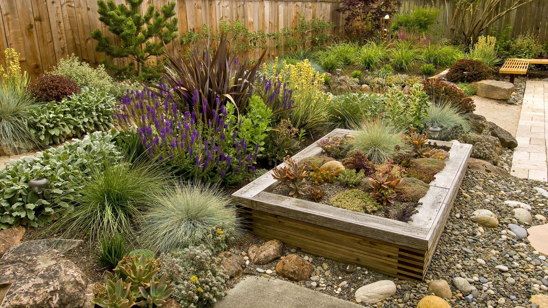 a garden with pebbles and stones and a wooden planter