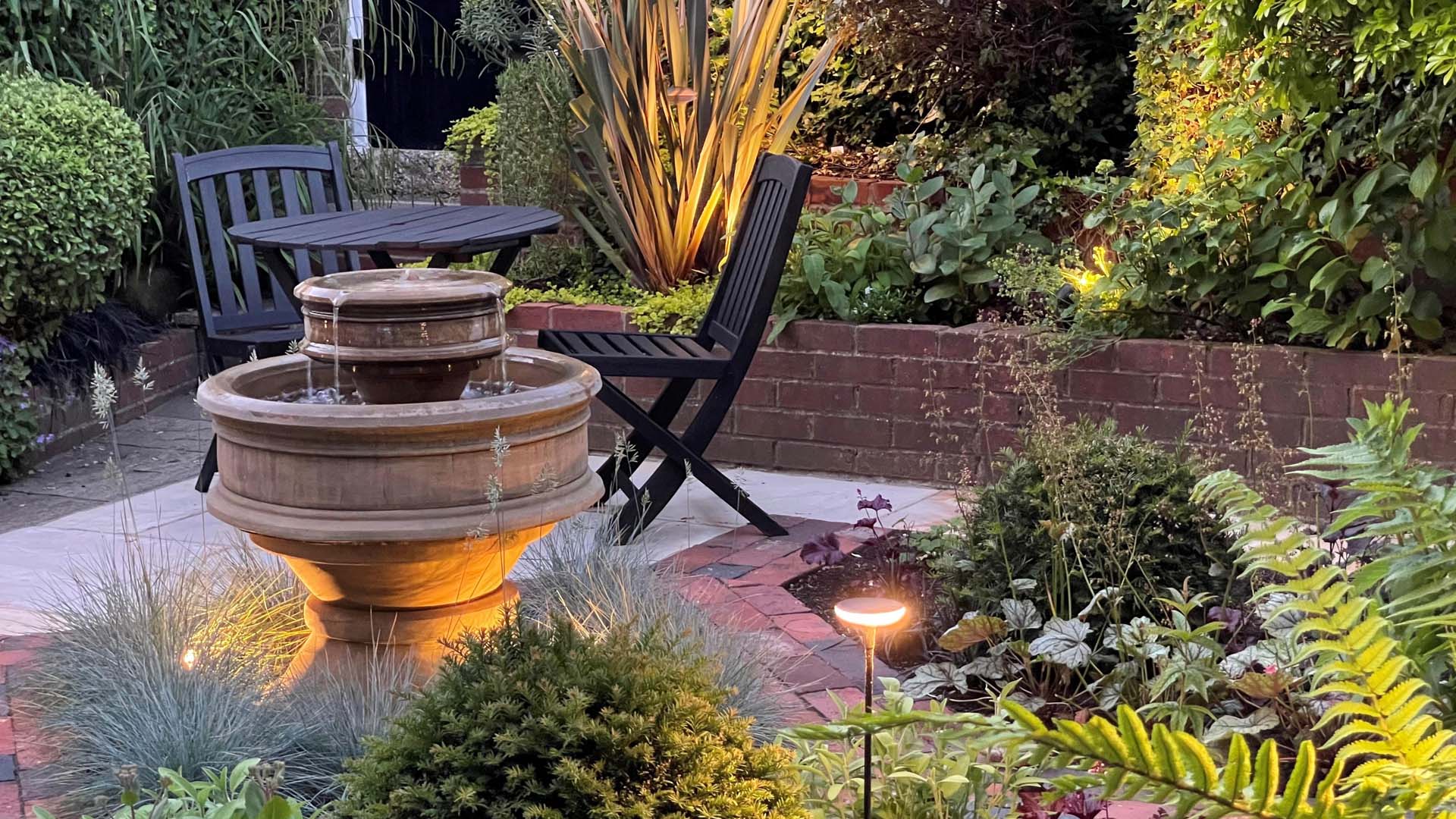 Small courtyard garden with water fountain and two chairs