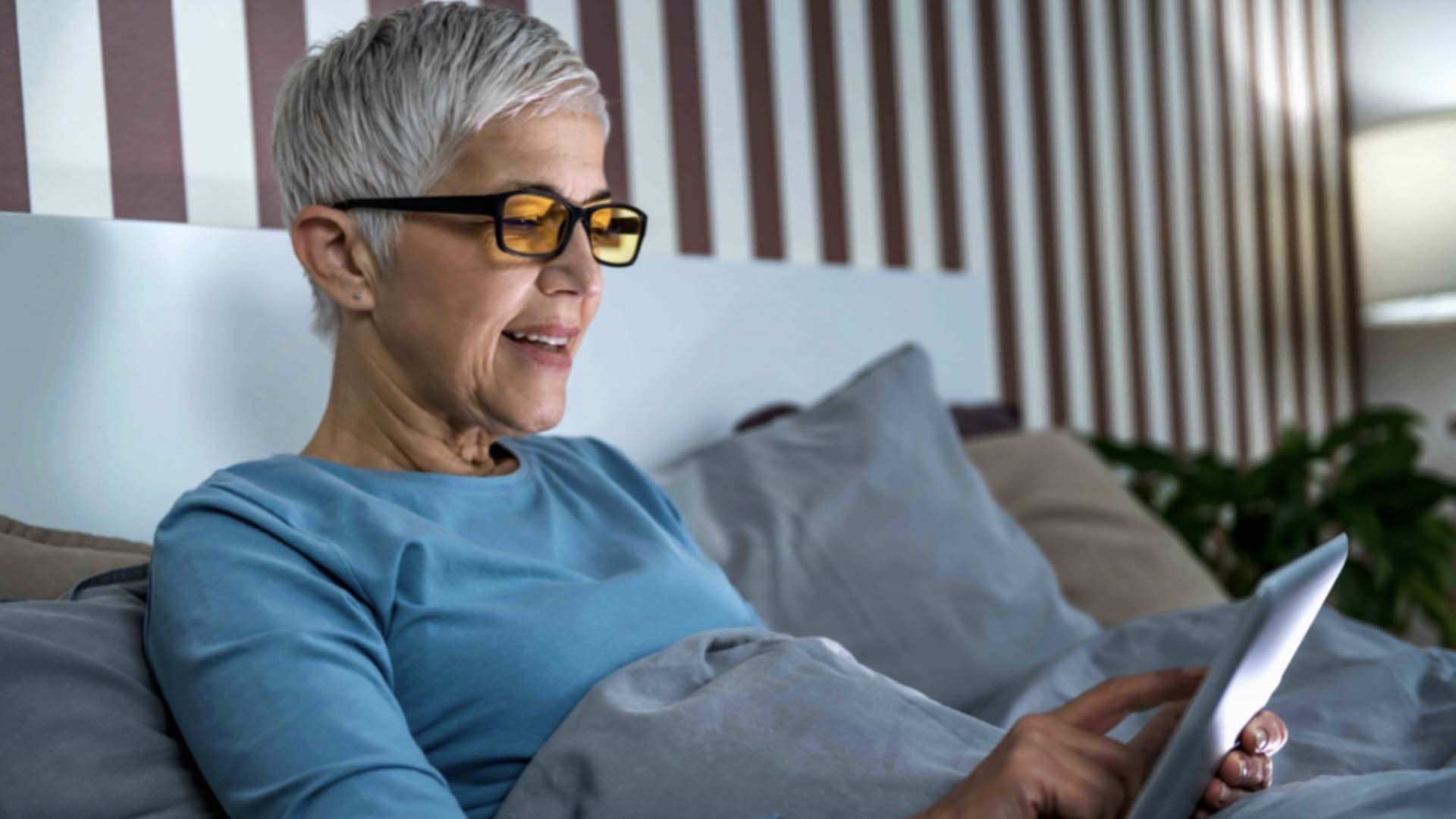 Woman looks at iPad in bed