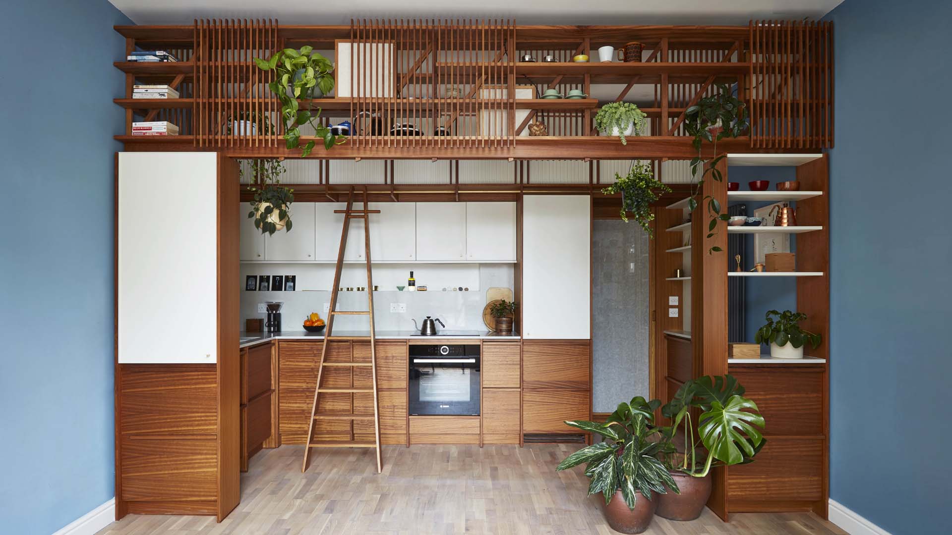 A kitchen with wooden units and blue-grey walls