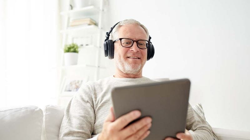Older man wearing headphones learning online