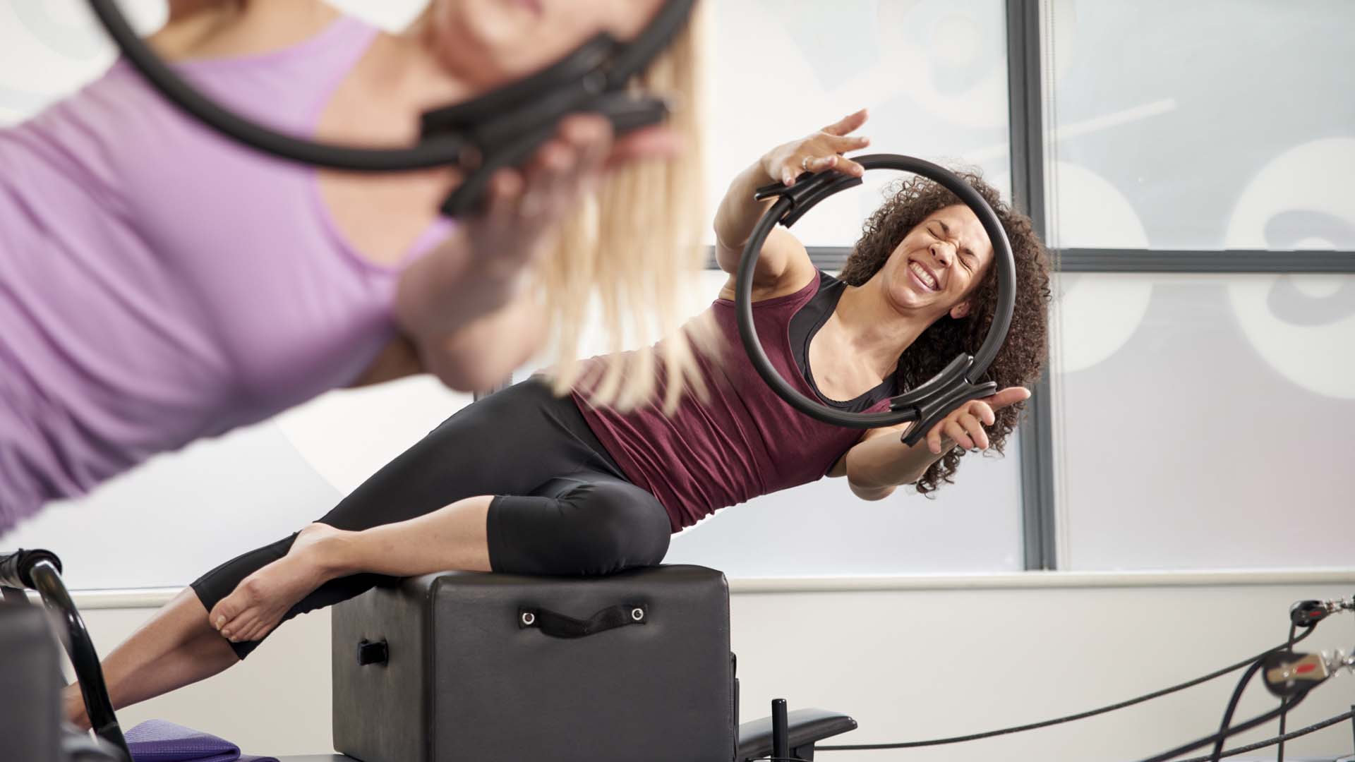 Women doing Pilates exercises using a block and other equipment.
