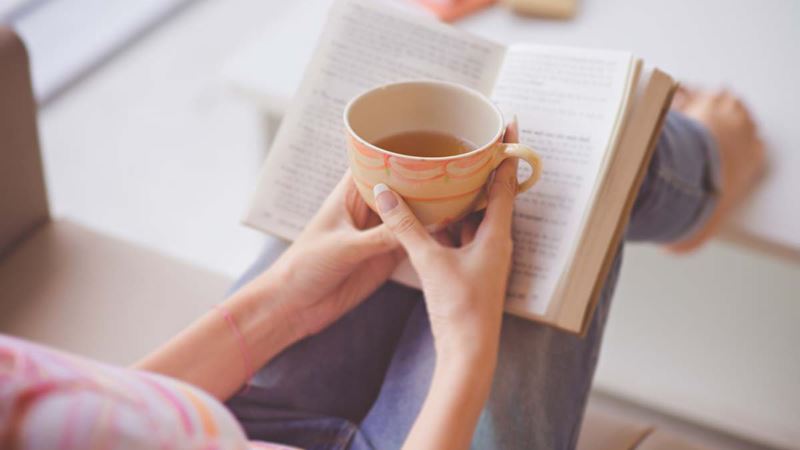 Woman relaxing with a book and a cuppa