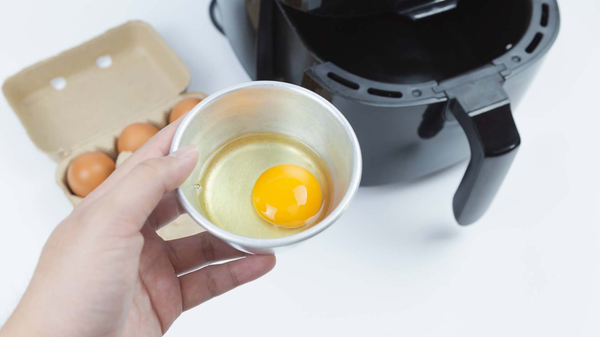 A person putting eggs into the air fryer