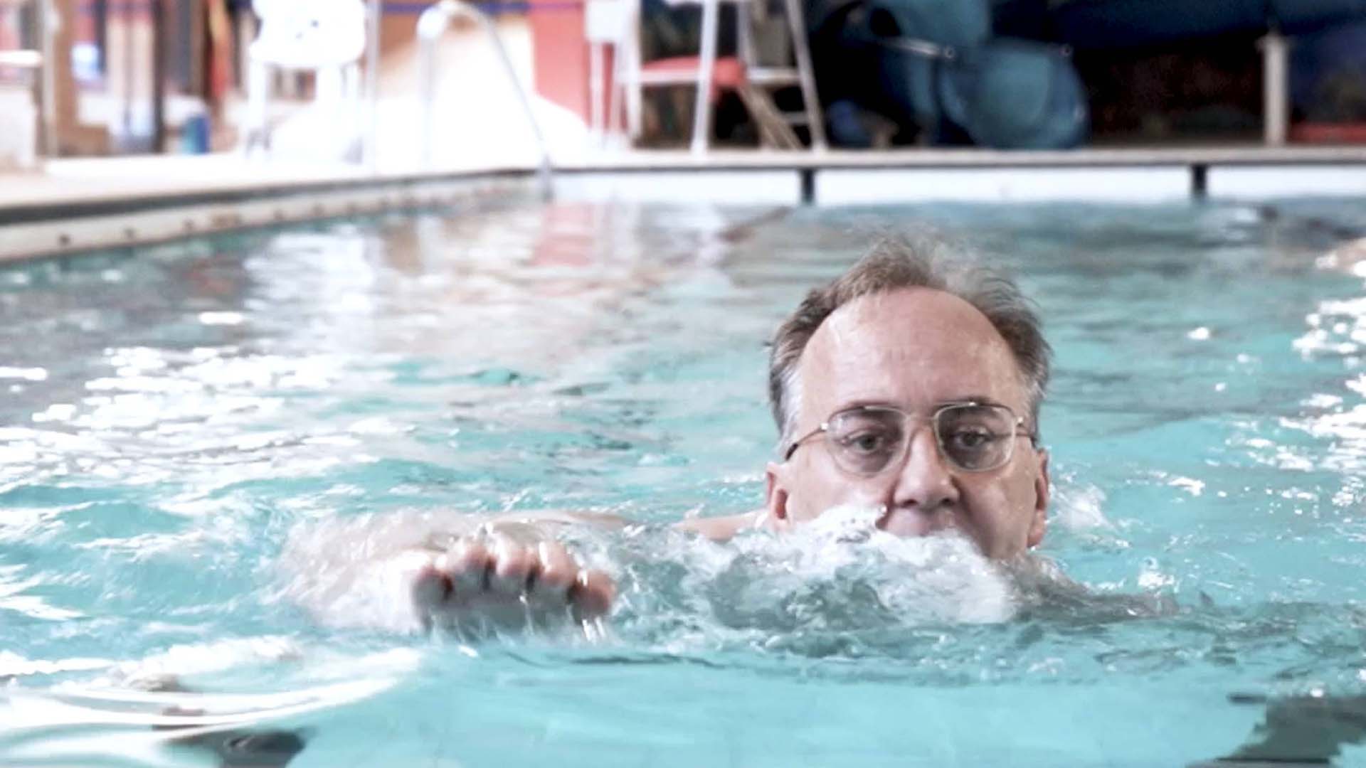 An older man swimming in an indoor pool