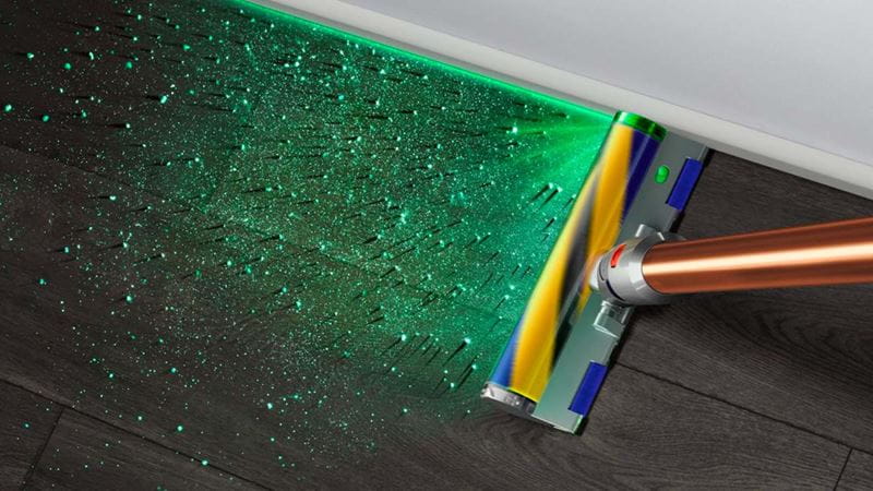 A Dyson vacuum with an illuminated cleaner head which projects a green light to show dust particles.