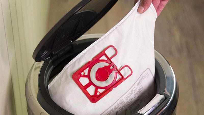 Close-up of someone putting a vacuum cleaner bag into a pedal bin