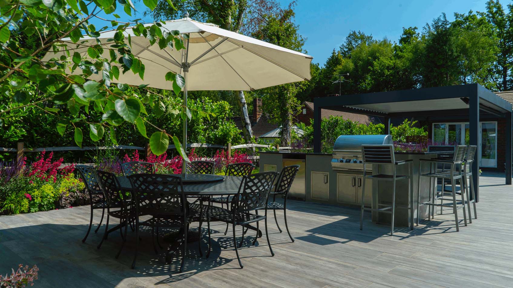 Parasol and metal round table with dining chairs alongside raised bar seating area