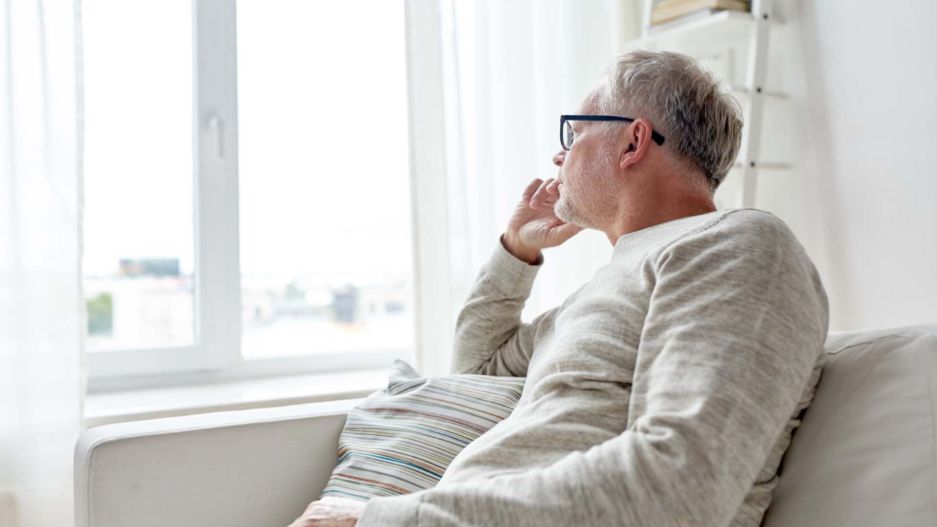 An older man stares out of his window