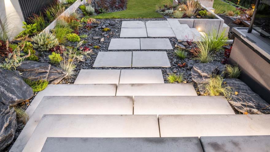 Garden steps in a slope, made with light stones, surrounded by various types of dark stones and gravels