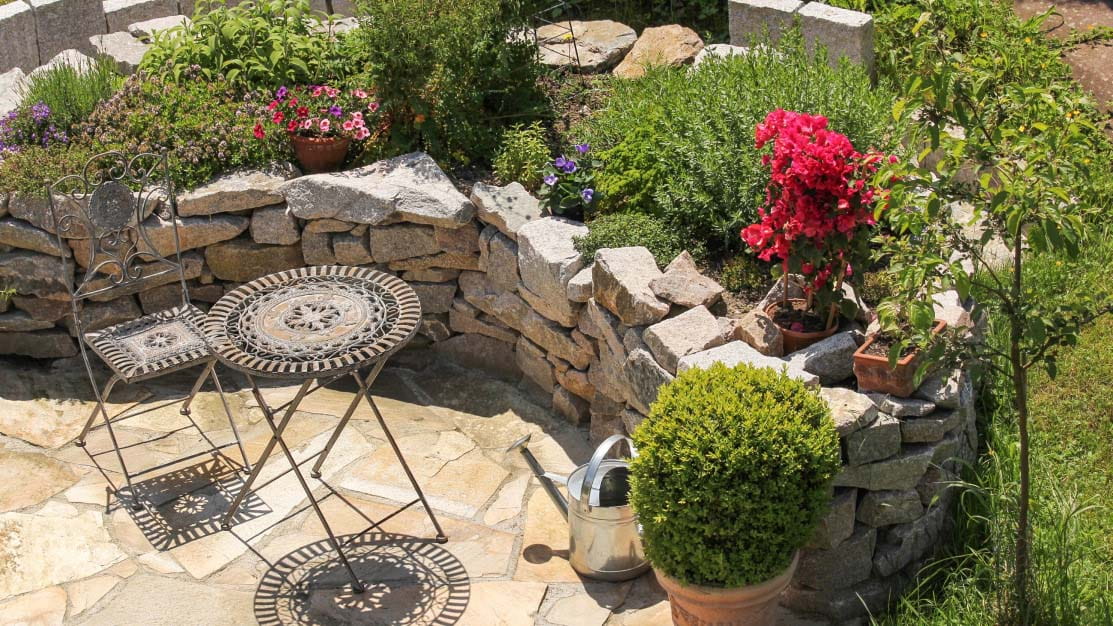 Paved garden surrounded by stone wall and rockery