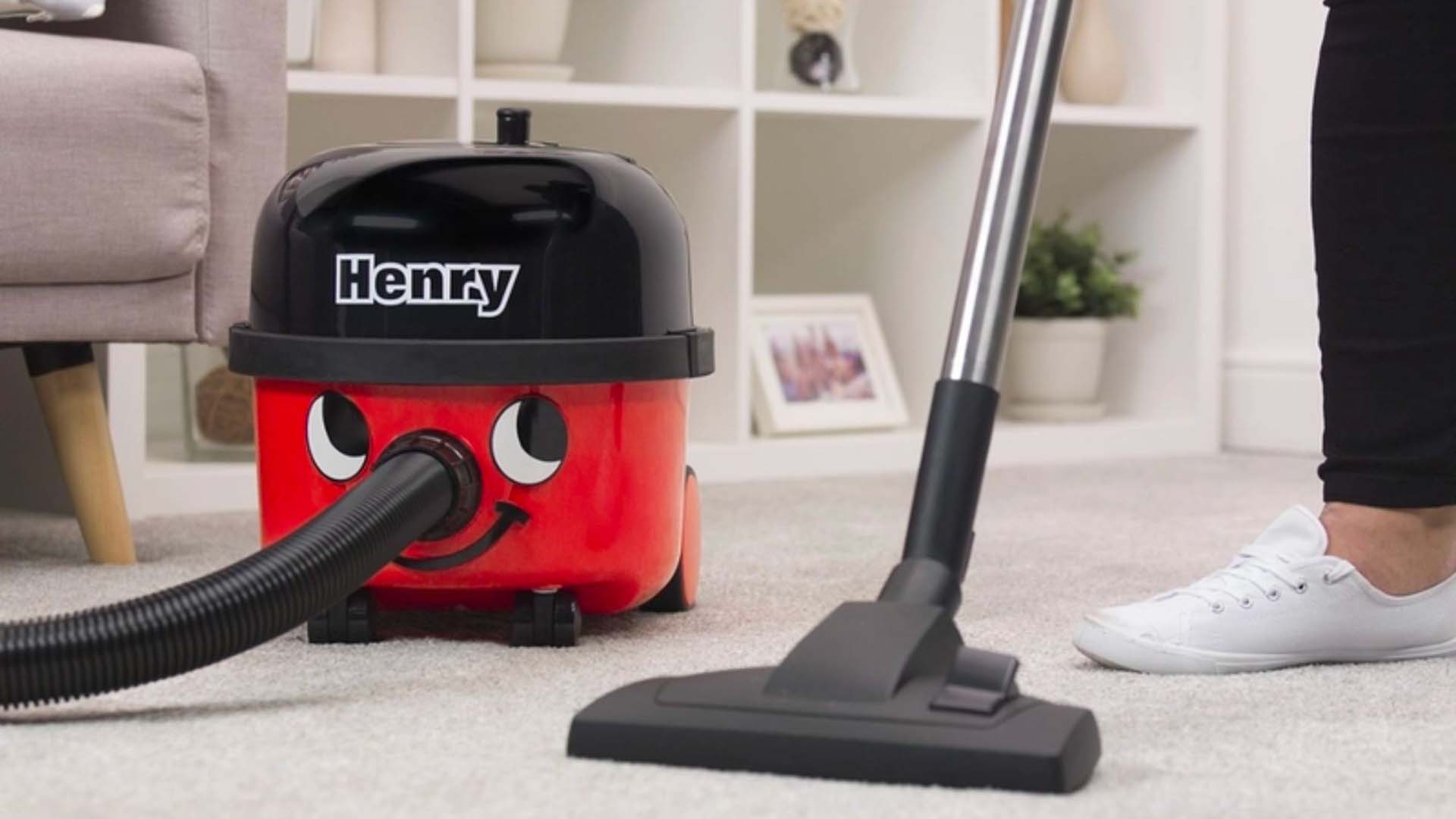 Someone using a Henry vacuum to hoover living room carpet