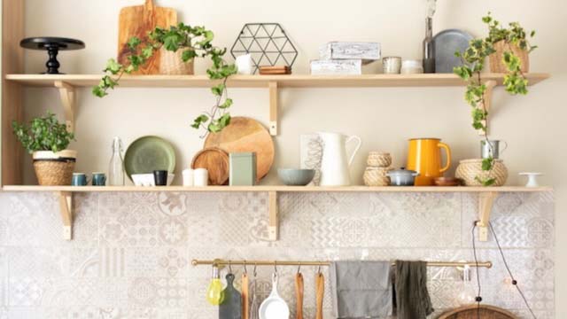 Stylish scandi cuisine interior decor. Ceramic plates, dishes, utensils and cozy decor on wooden shelfs. Kitchen wooden shelves with various ceramic jars and cookware. Open shelves in the kitchen.