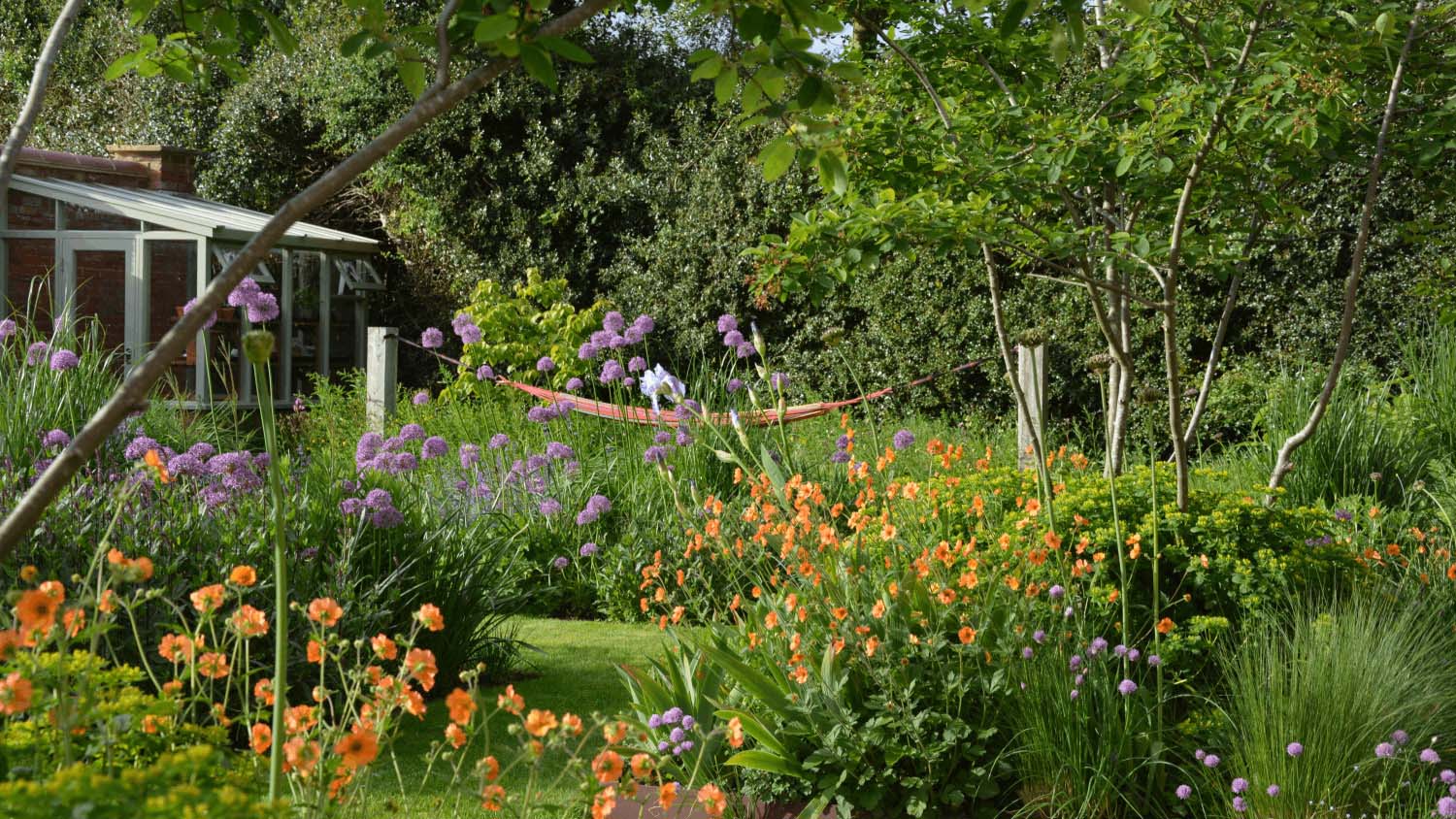 A hammock hang on two large existing structures in the middle of a wild garden