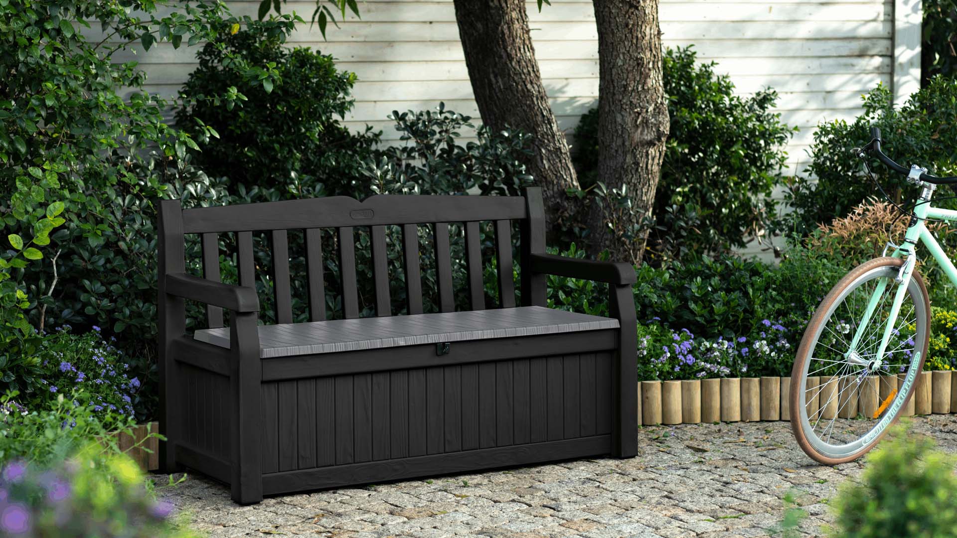 Seating and storage dark waterproof bench in front of a tree in the garden
