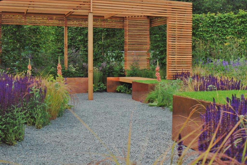 A basalt gravel pathway flanked by raised flower beds
