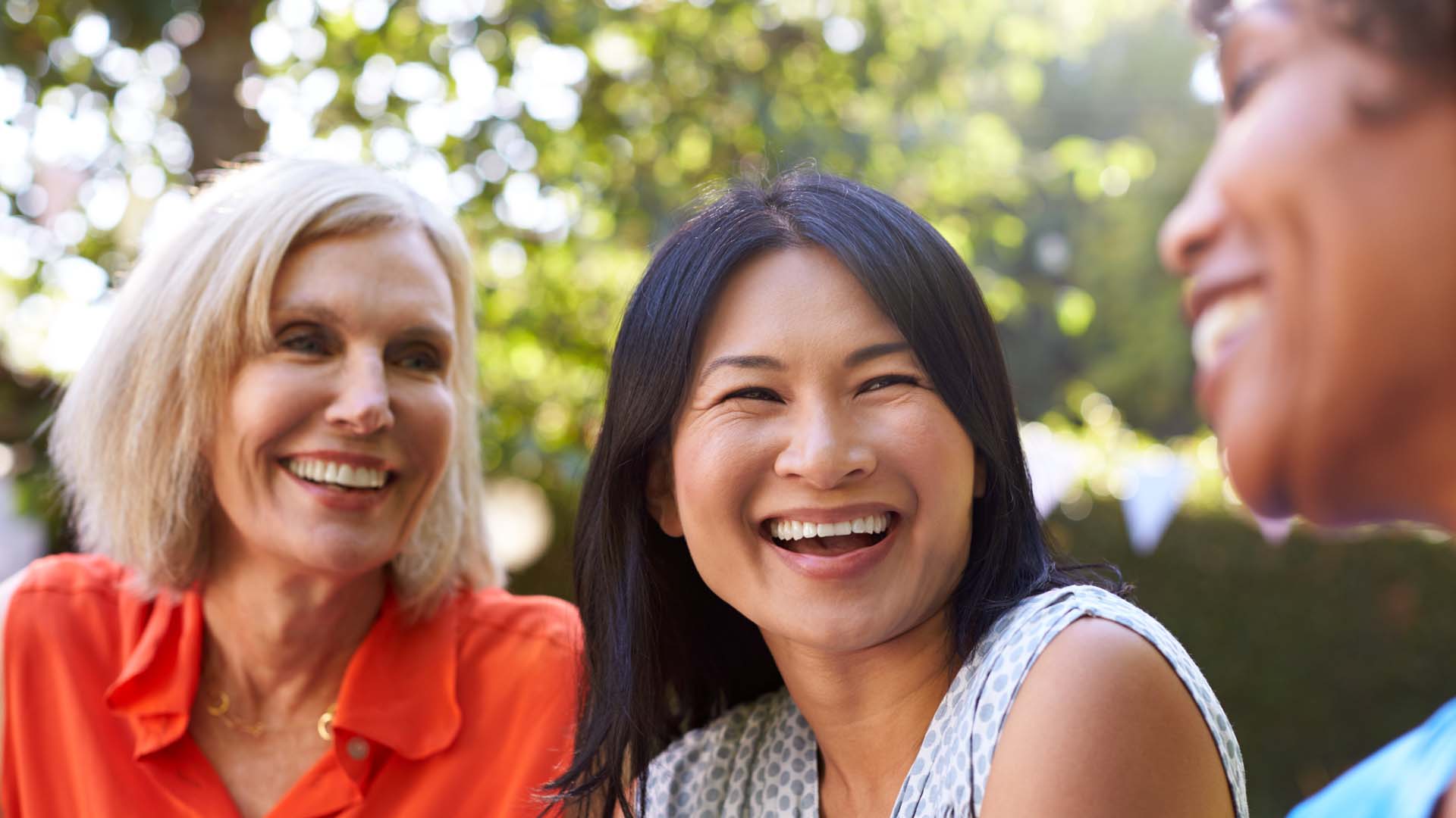 Three smiling women outdoors on a sunny day