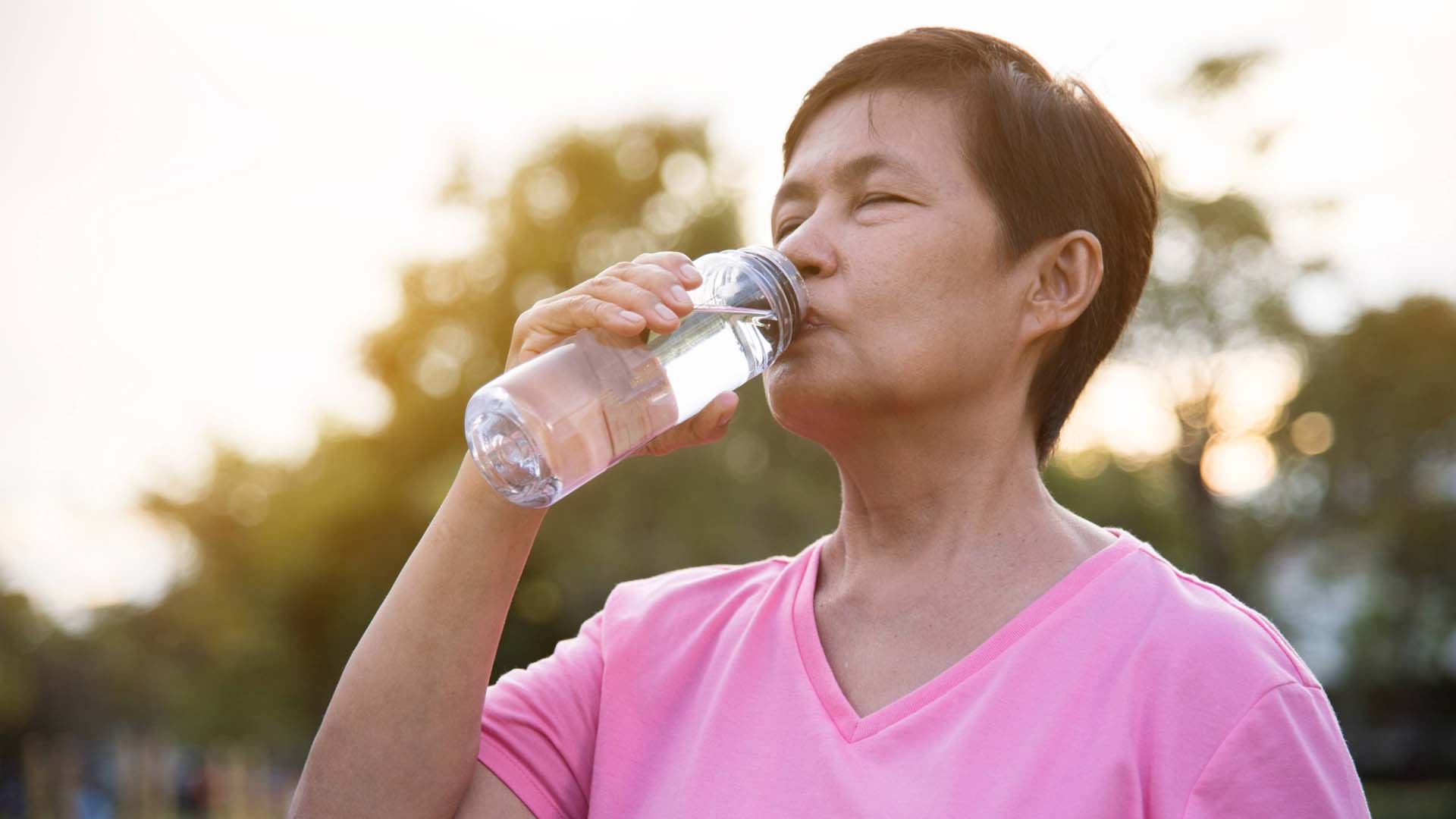 An older woman takes a drink of water