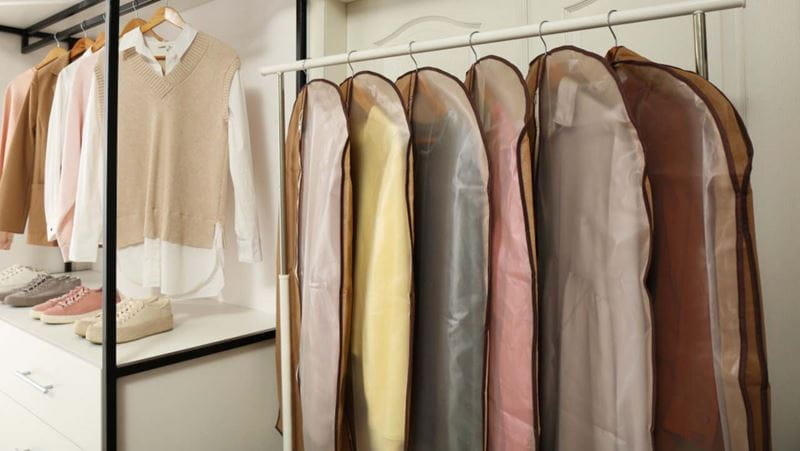 Garment bags with clothes on rack in dressing room