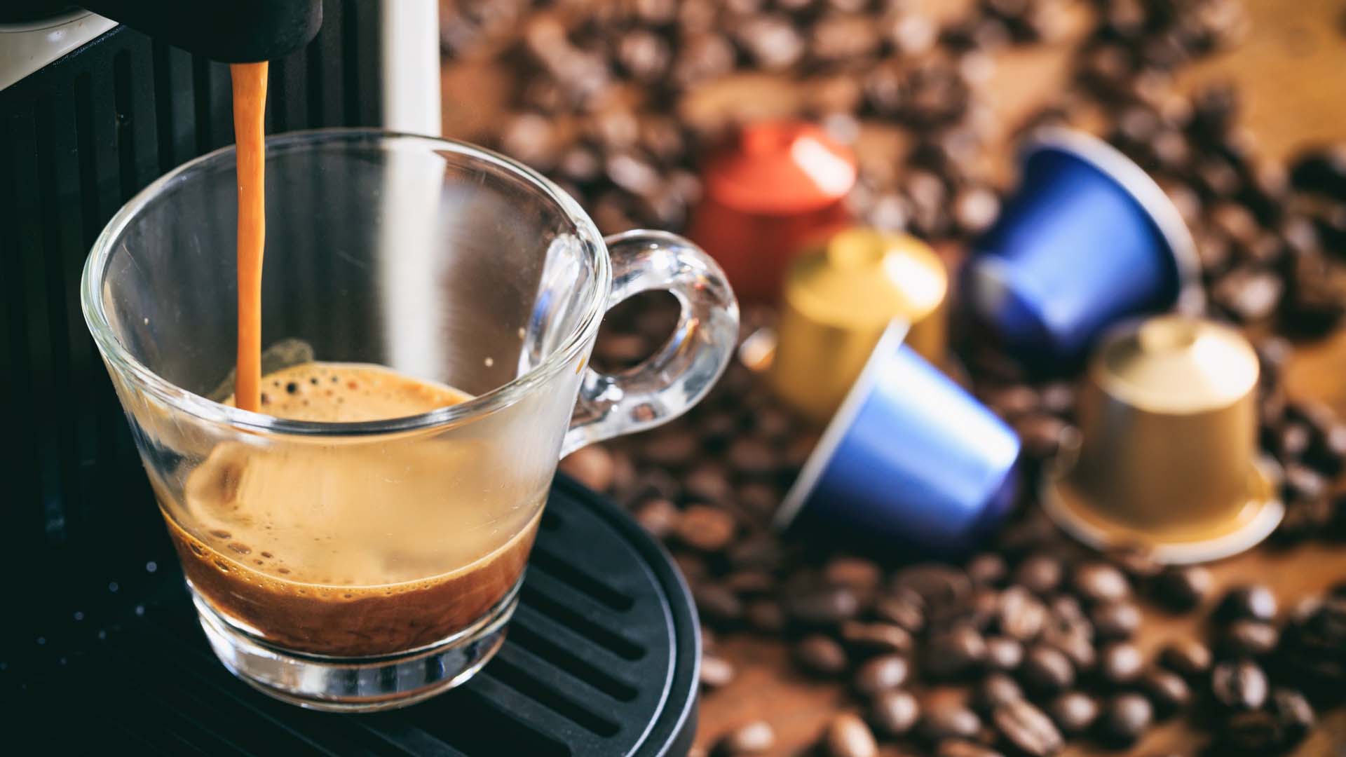 a coffee machine surrounded by beans and pods