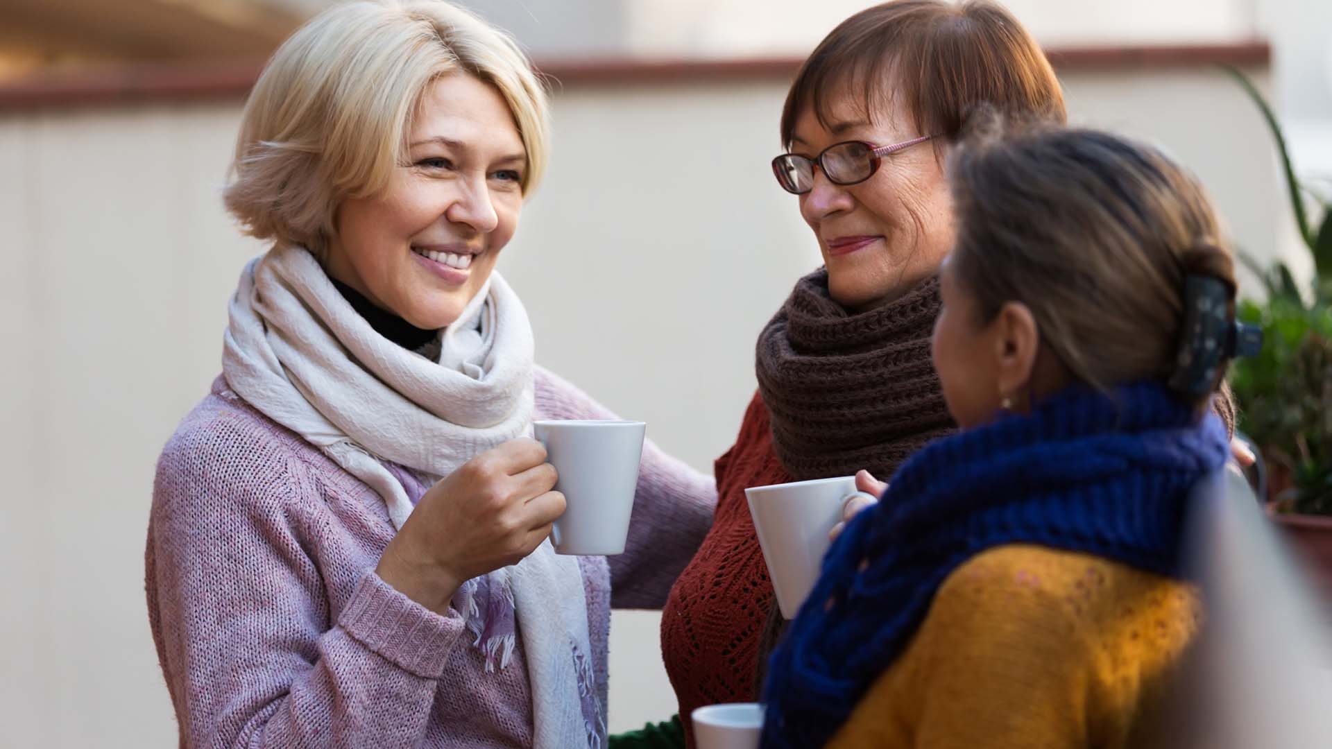 Three women socialising with hot drinks