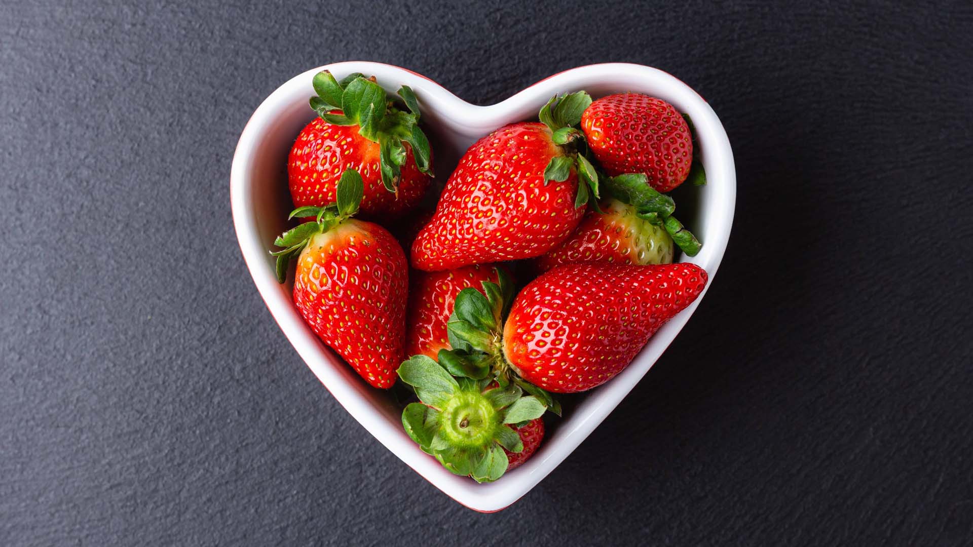 fresh ripe strawberries in a heart shaped bowl