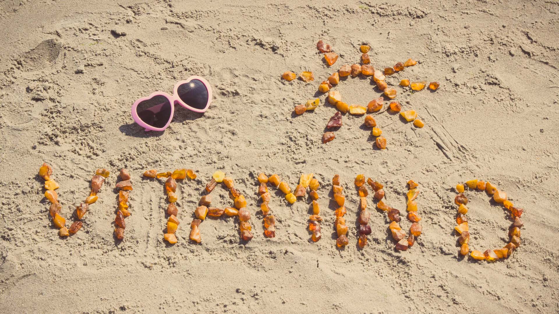 Vitamin D written in the sand with shells