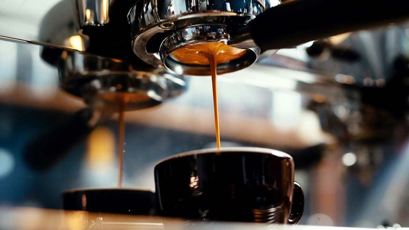 A coffee machine pours espresso into a mug