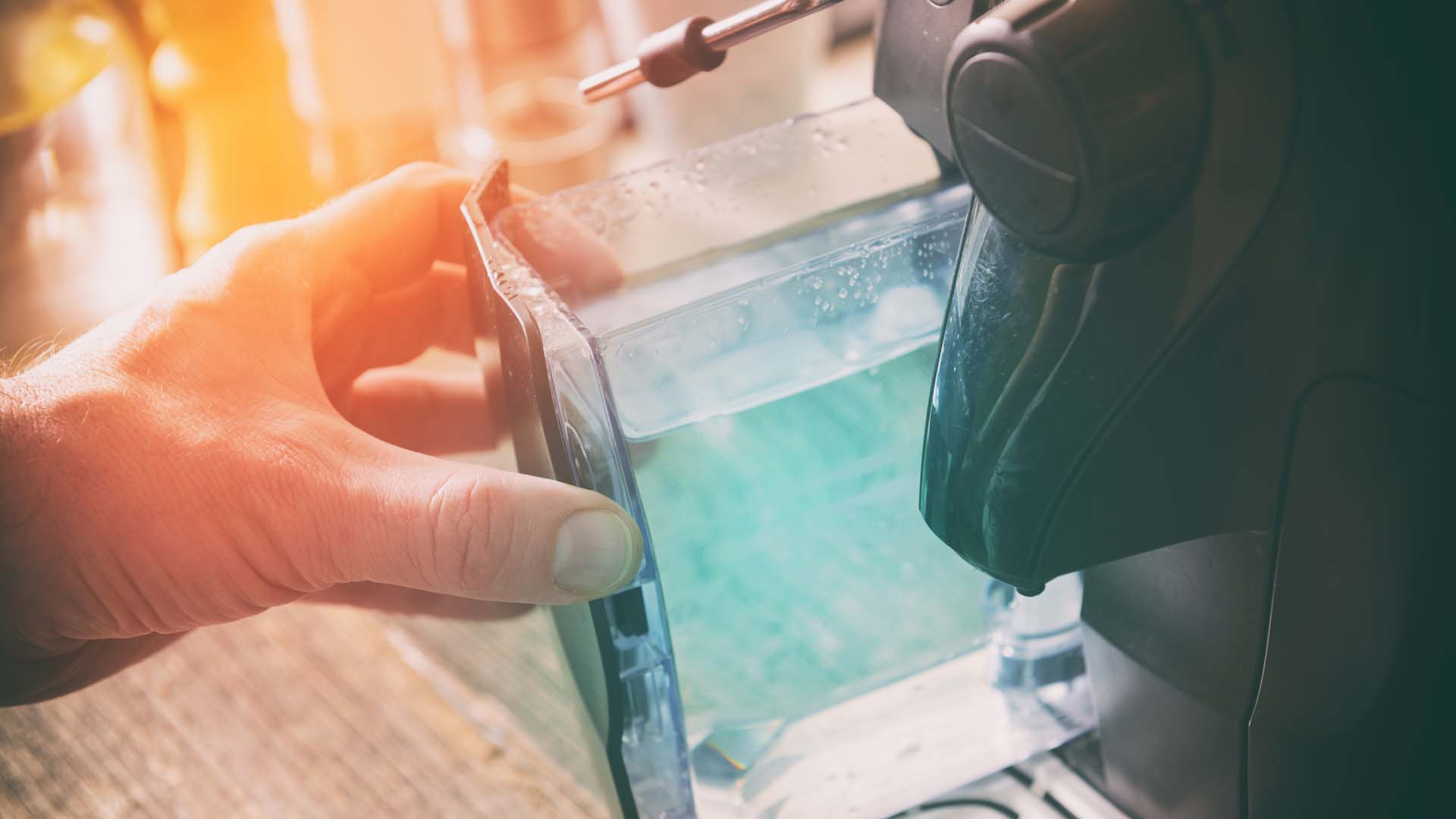 A coffee machine water reservoir being removed