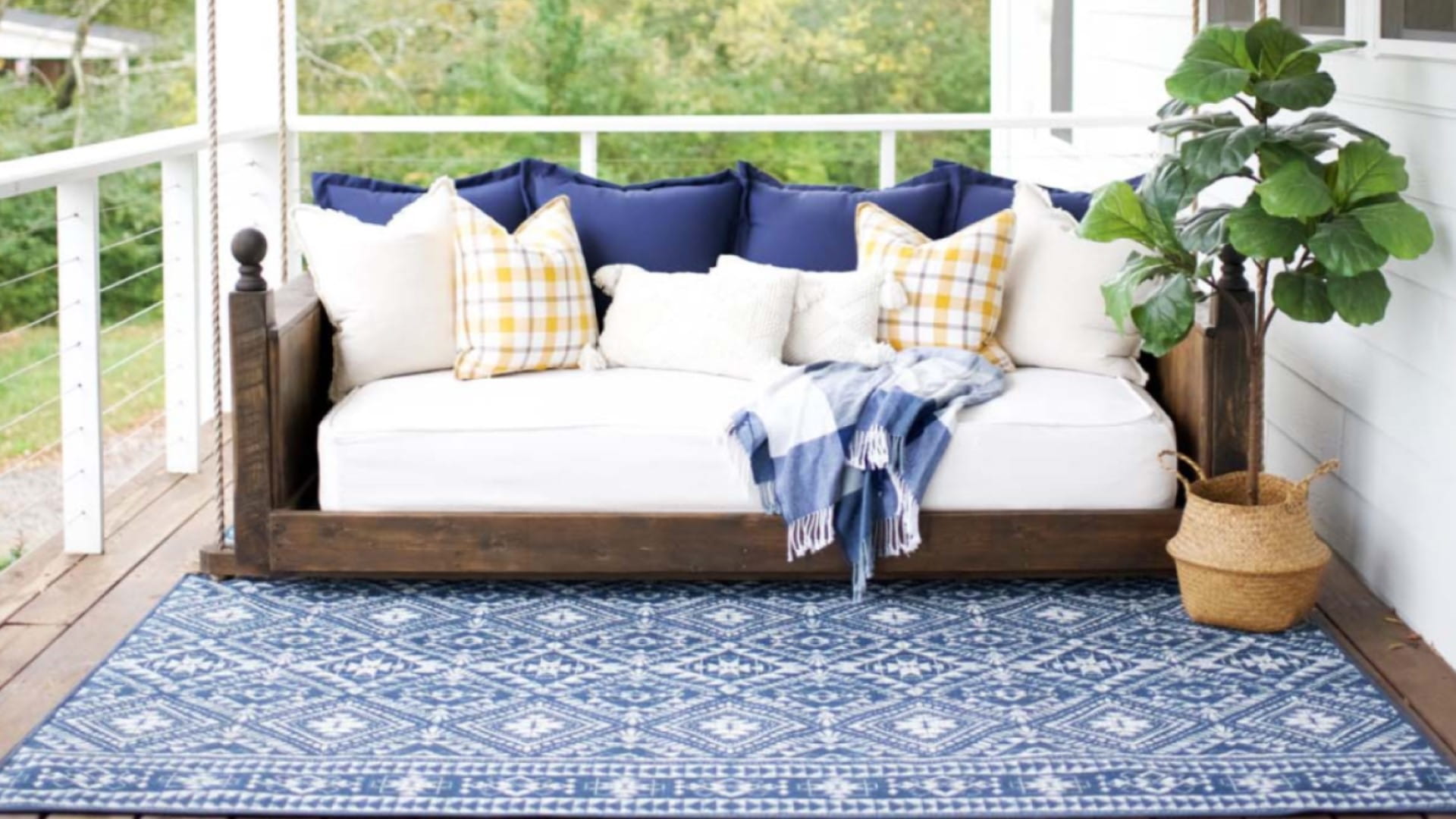 A homey balcony space with a rug, plant and sofa with cushions