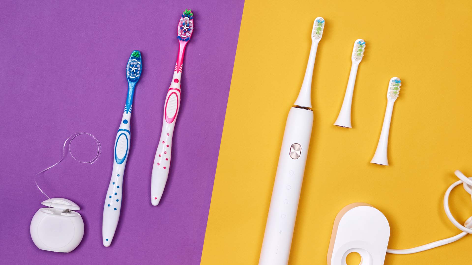 Electric and manual toothbrushes side by side with floss and a charger