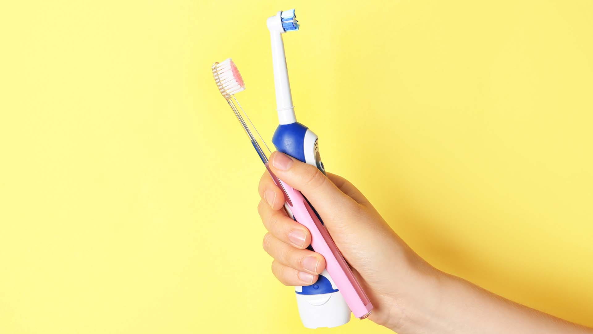 Electric and manual toothbrushes held in a hand