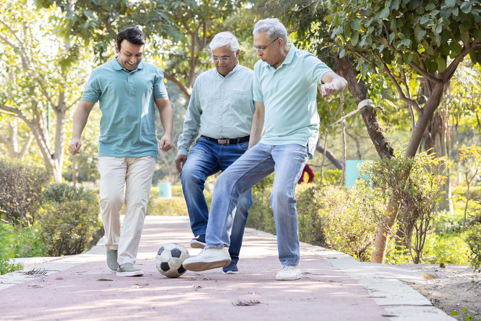 Three older men playing kickabout with a ball