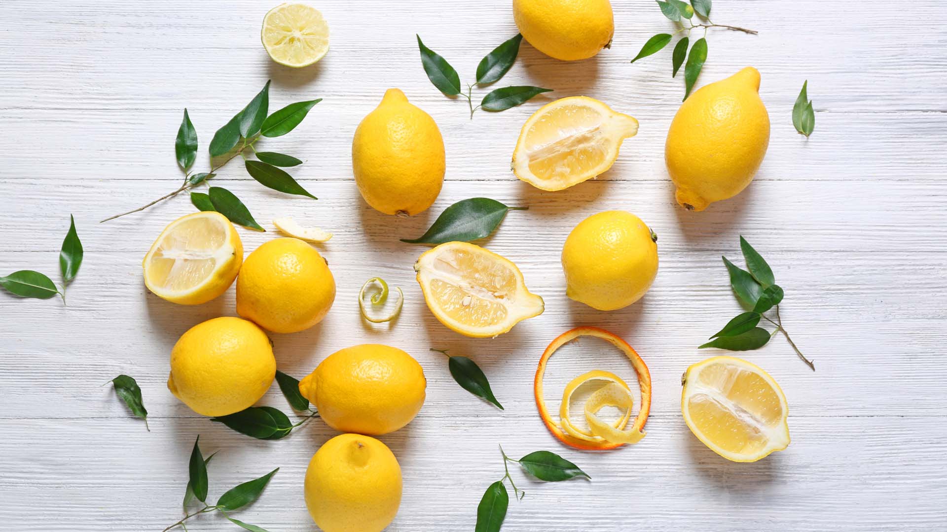 A flat lay of whole and cut lemons with their leaves
